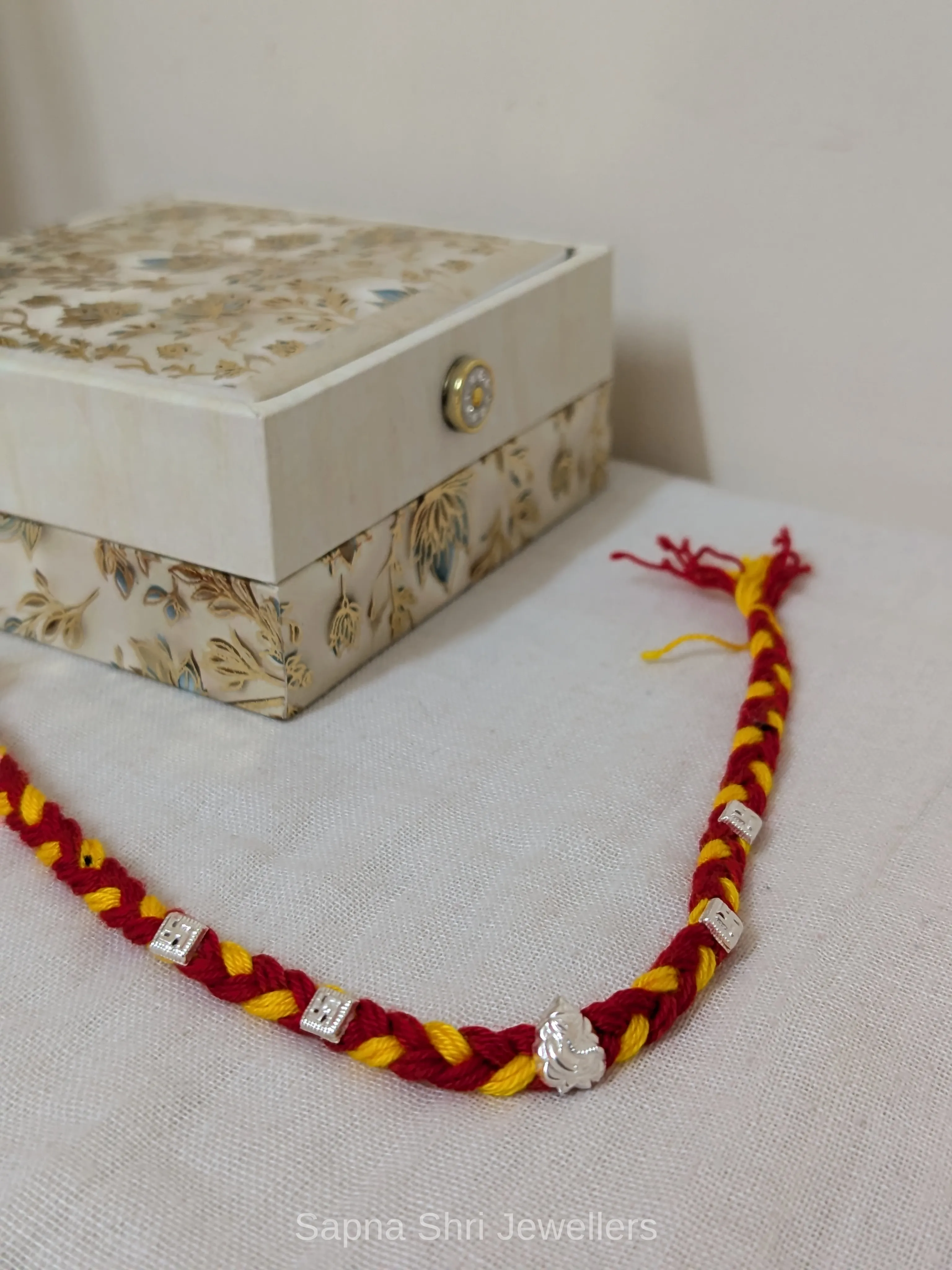 Ganesh Silver Rakhi – Red & Yellow Mauli Rakhi for Brother - Image 1 of 4 Ganesh Silver Rakhi – Red & Yellow Mauli Rakhi for Brother - View 1