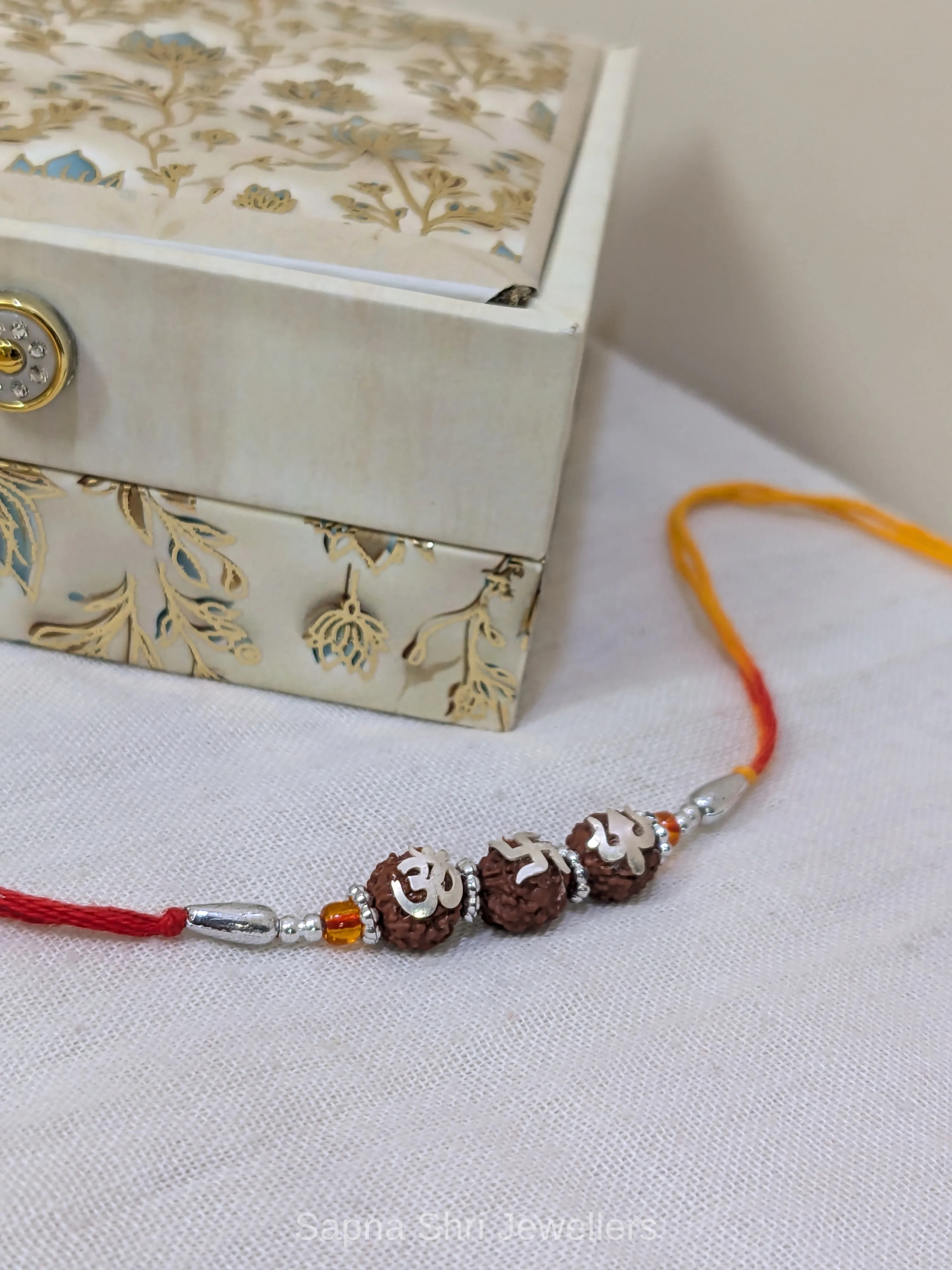 925 Silver Om Swastik Trishul Rudraksha Rakhi with Red & Yellow Mauli - Image 1 of 4 925 Silver Om Swastik Trishul Rudraksha Rakhi with Red & Yellow Mauli - View 1